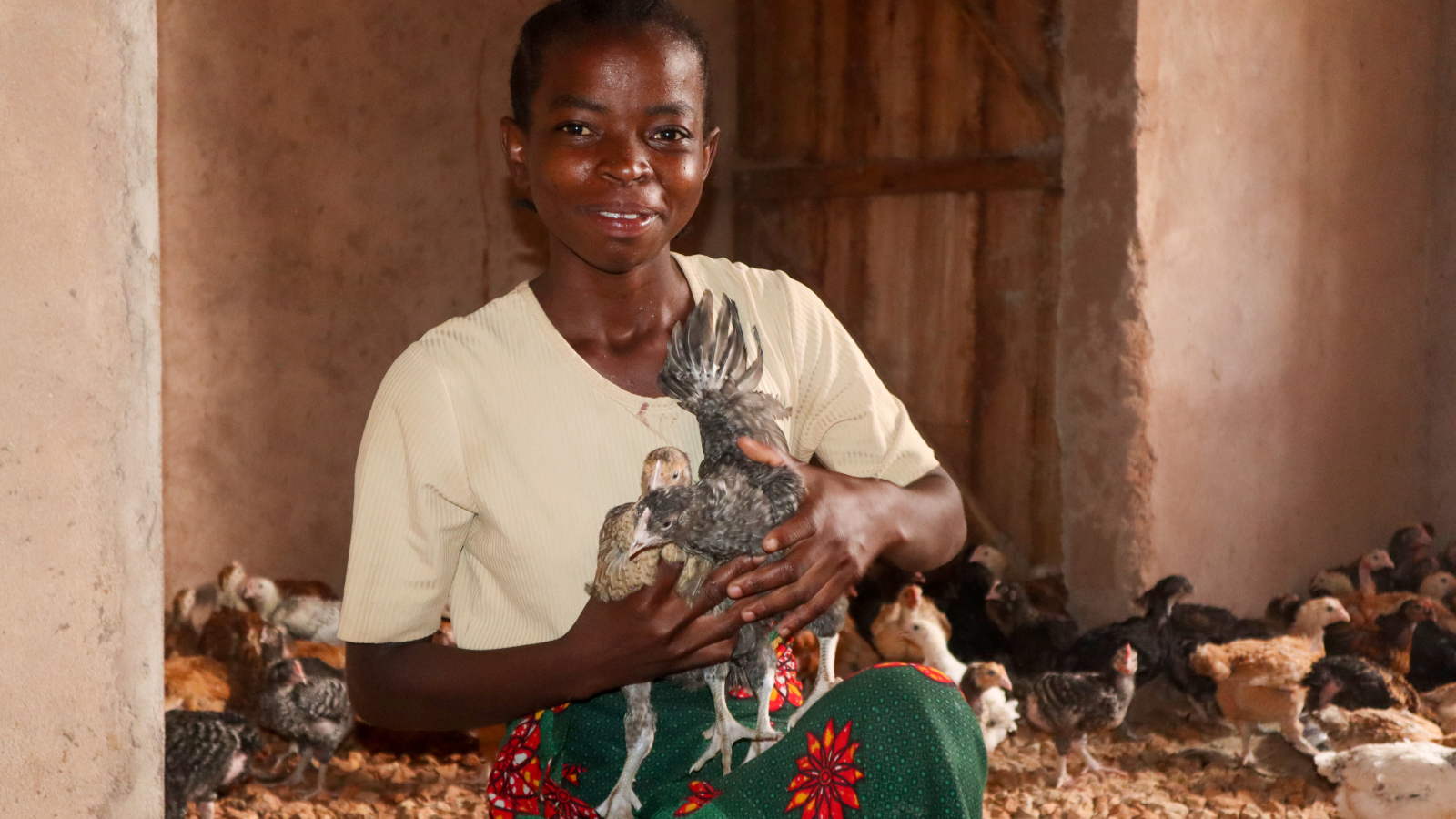 Smiling face from Grace Mteli holding her first 4 weeks brooded chicks