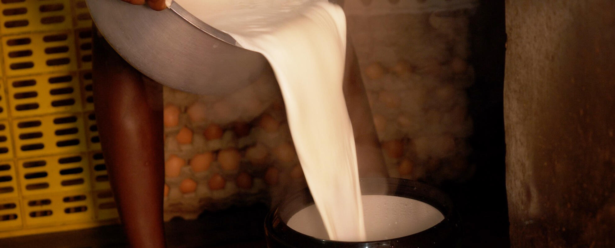 Person pouring boiled milk from a saucepan into a milk container