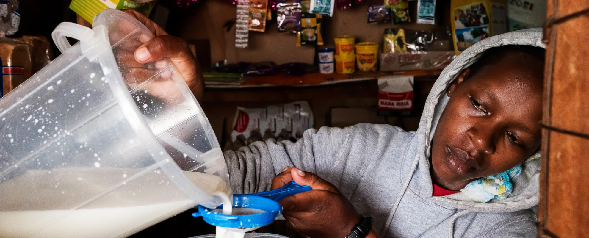 Nicole Mutai pours milk for a customer at her shop near Eldoret, Kenya