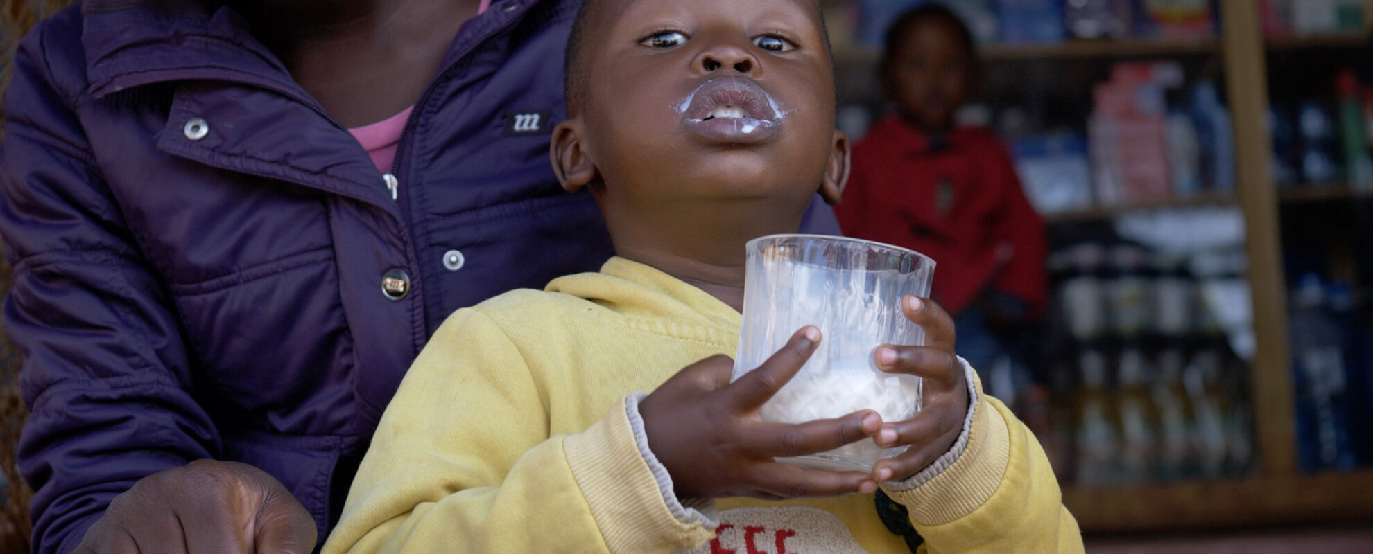 A boy drinking milk outside of a milk shop in Nairobi, Kenya. Photo ILRI/Shadrack Isingoma 